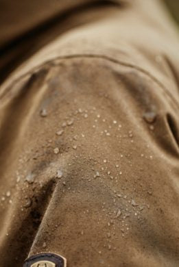 Water droplets beading on brown water-resistant Ariat Argentium Parka sleeve showing weatherproof fabric performance