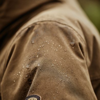 Water droplets beading on brown water-resistant Ariat Argentium Parka sleeve showing weatherproof fabric performance