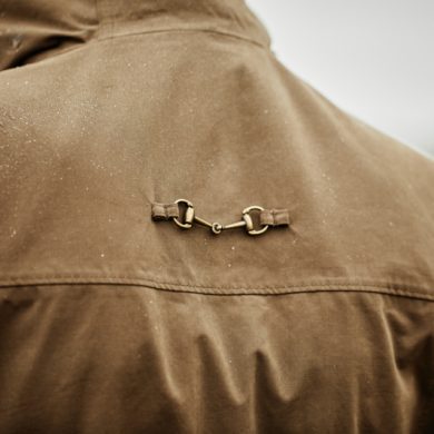 Bronze-tone horse bit clasp detail on back yoke of brown Ariat Argentium Parka jacket