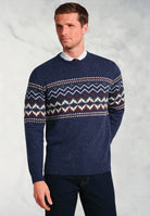 Man wearing navy blue Ainslie Fairisle crew neck sweater with traditional pattern in white, burgundy and green over shirt