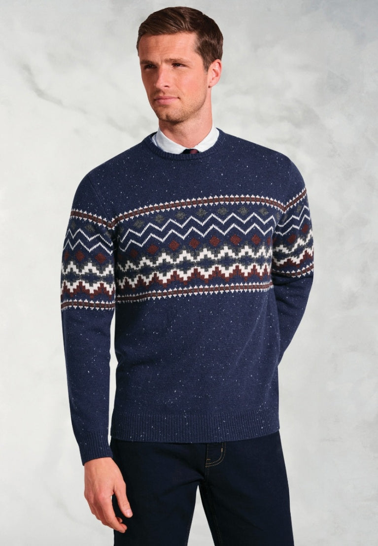 Man wearing navy blue Ainslie Fairisle crew neck sweater with traditional pattern in white, burgundy and green over shirt